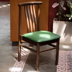 A custom-designed wooden chair with a green upholstered seat. We work closely with furniture makers to create bespoke pieces that perfectly match the material palette and design intent of our projects.