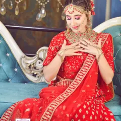 A full view of this gorgeous bridal look. The intricate red lehenga is paired with a detailed hairstyle and traditional jewellery, including a maang tikka and nath. The makeup is designed to be flawless both in person and in photographs.