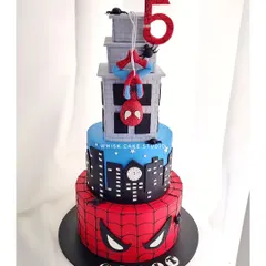 A grand, four-tiered Spider-Man cake. This impressive structure features the city skyline, a web-covered base, and Spidey hanging from the top.