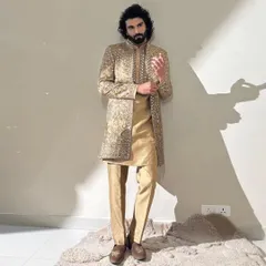 A full shot of a model in a stunning golden sherwani. The grooming here was key to making sure his face looked as regal as the outfit, with clear skin and perfectly styled hair and beard.