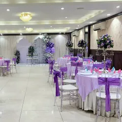 A wider view of our Eid celebration setup, showing the guest dining tables decorated to match the main backdrop with purple linens and chair sashes.