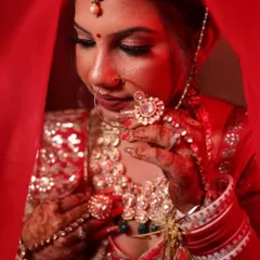 A dramatic and artistic shot of a bride in her red wedding attire. The lighting highlights her features and the rich color of her outfit, creating a truly memorable portrait.