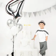 Standing proud by his birthday cake and balloons. A fourth birthday is a big deal, and this young man is ready for his portrait.