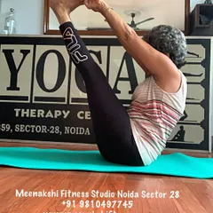 Holding the boat pose. This demonstrates the core strength required to keep the spine straight and legs lifted.
