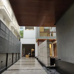 The completed entryway of a modern home, with polished marble flooring, a wood-paneled ceiling, and a finished marble feature wall.