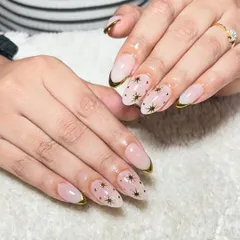A celestial-inspired design with a nude base, gold-lined French tips, and delicate gold star art.