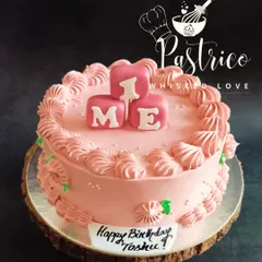 A pretty pink cake for a baby girl's first birthday, with "ONE" spelled out in cute blocks.