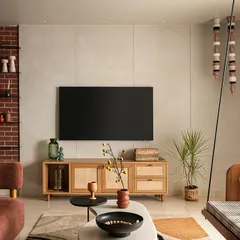 The TV wall is a focal point, finished in a soft micro-topping to create texture and depth. The minimal TV console uses rattan shutters to hide wires, and brick cladding on the side connects it to the rest of the living space.
