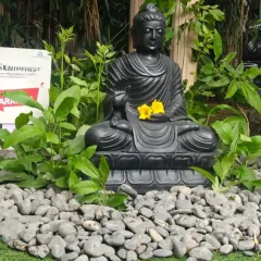 Another view of the black marble Buddha statue, adorned with yellow flowers, showcasing how this single element can become the focal point of a peaceful garden corner.