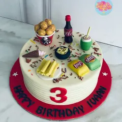 A feast for the eyes and taste buds! This fun fast-food-themed cake for a 3rd birthday is topped with all the favorites: KFC chicken, Lays chips, Coke, and fries, all in edible form.