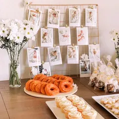 Make your celebration deeply personal with a custom photo display. Here, we used a gold grid to hang sweet polaroid photos of the baby, creating a beautiful and sentimental addition to the dessert and gift table.