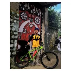 A rider posing with his bike in front of a traditionally carved wooden gate in an Angami Naga village. Our tours are as much about cultural immersion as they are about cycling.