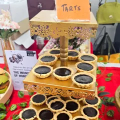 A three-tiered stand filled with rich chocolate tarts. This elegant presentation makes them a centerpiece of the dessert table at any event.