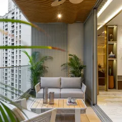 A cozy and modern balcony setup. The comfortable woven sofa and armchair are perfect for lounging, while the wooden ceiling detail and potted plants create a natural, resort-like feel.
