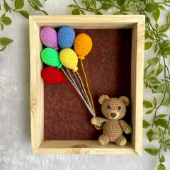 A cheerful nursery frame with a little teddy bear holding a bunch of rainbow-colored balloons. This piece is sure to brighten up any child's room.