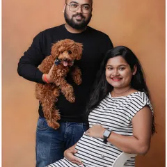 A simple and classic studio maternity portrait of a couple with their pet dog. This shows how we can include your furry friends in this special milestone.