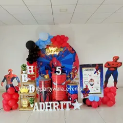 This Spiderman setup for a 5th birthday includes character cutouts, a personalized milestone board, and themed cylinders, making it a complete package for any young fan.