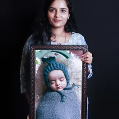 A beautiful way to display your photos. Here, a mother holds a framed print from her baby's newborn session, showing the high-quality products you can order.