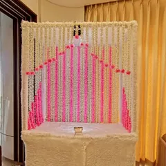 An elegant home mandir decorated with strings of mogra (jasmine) and pink flowers. This simple yet beautiful setup is perfect for creating a serene space for daily prayers or small festivals.