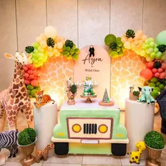A 'Wild One' safari party is always a favorite. I focus on creating a fun and friendly jungle atmosphere with life-sized animal props like a giraffe and elephant, a custom jeep-shaped table for the cake, and balloon garlands that match the safari color palette.
