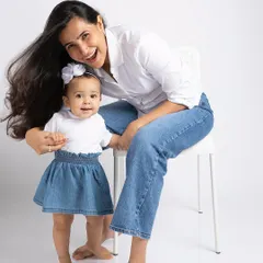 Twinning in denim. This mother and daughter share a beautiful, happy moment, showcasing their special bond in a fun, casual portrait.
