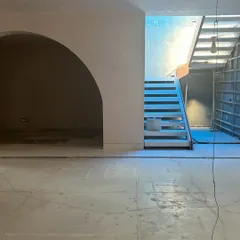 The process begins with a blank canvas. This was the living area of the Quiet Ornate home in March 2024, a raw space full of potential, with the basic structure of the archway and staircase in place.