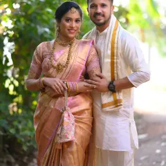 A beautiful portrait of a newly married couple in their traditional South Indian wedding attire. The soft outdoor lighting enhances the glow of the bride's silk saree and the couple's happy expressions.