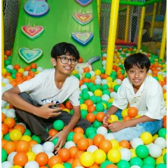 The indoor play zone is the heart of the fun. Here, friends share a laugh in the colorful ball pit, one of the many safe and exciting play structures available for endless entertainment.