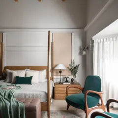 A shot from our AD India feature, showcasing a master bedroom with a teakwood four-poster bed, sea-green velvet armchairs, and a high, sloping ceiling with teak rafters.