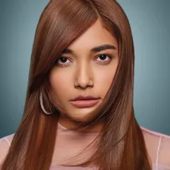 A stunning beauty portrait with a focus on luminous, perfect skin and soft, copper-toned hair. The makeup is understated and elegant, enhancing the model's natural features for a high-end commercial look.