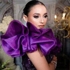 The entire look is about drama and elegance, from the ruffled sleeves to the sharp, clean makeup.
