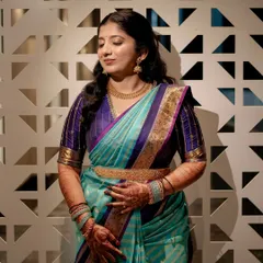 A candid moment showing the client's serene expression. The henna design is visible on her arms, beautifully complementing her traditional attire and jewelry.