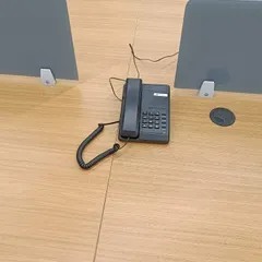 A basic telephone handset placed on an office desk, connected to the central EPABX system for internal and external calls.