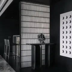 The entrance console and bar area in the Vaulted Haus are separated by a vertical partition of frosted solid glass bricks. The material's ability to refract light creates a soft glow, dividing the space while maintaining a visual connection.