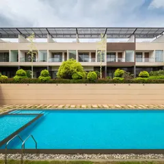 The linear design of the pool is complemented by the soft textures of the surrounding landscape. Paving stones with grass joints and structured green pockets break up the hardscape, creating a harmonious rhythm that connects the built form with the natural environment.