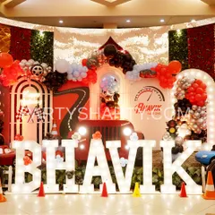 A powerful stage setup for a car lover's birthday, featuring a large jeep prop, marquee letters, and a backdrop with a race track design.
