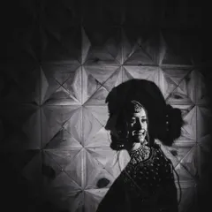 An artistic double-exposure bridal portrait in black and white. This creative technique blends the bride's silhouette with her smiling profile, resulting in a unique and memorable piece of photographic art.