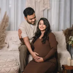 A loving couple poses in a warm, bohemian-inspired studio. The earthy brown tones and natural textures create a cozy and intimate atmosphere.