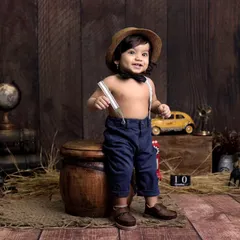 A dapper little gentleman in our vintage explorer setup. The dark wood background, antique props like a globe and lantern, and classic attire create a timeless and charming look.