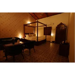 This spacious suite at the resort features classic dark wood furniture, including a four-poster bed and a large armoire. The patterned floor tiles and warm lighting create a sense of old-world elegance and comfort.