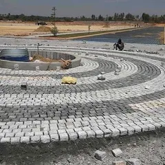 This shows the process of creating a large circular pattern with cobblestones. Each stone is laid by hand to ensure a perfect fit and a durable, long-lasting surface.