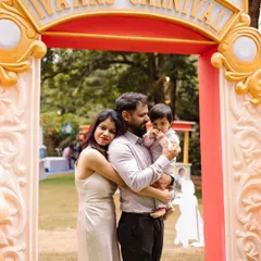 The family stands proudly at the entrance of "Ivaan's Carnival." The custom-designed arch sets the perfect tone for a fun-filled celebration.