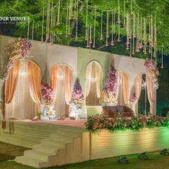 I designed this elegant reception stage with a backdrop of arched panels and soft pastel curtains. The hanging floral tassels and lush stage-front arrangements add layers of texture and romance.