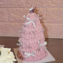 A very merry pink Christmas tree cake! This fun and festive creation is covered in textured pink frosting, sparkly details, and tiny white bows, perfect for a playful holiday celebration.