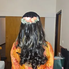 A soft, romantic half-up hairstyle with loose curls and floral accessories. This look is perfect for a baby shower, engagement, or any daytime event.