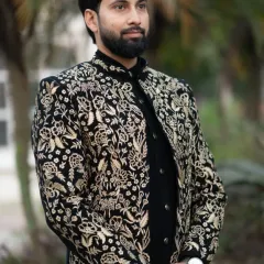 A close-up of the groom's black and gold embroidered Indo-Western jacket. The detailed floral and paisley patterns showcase our commitment to exquisite craftsmanship.