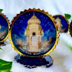 A close-up of one of the Taran Jayanti souvenirs. The image of the temple is set against a sparkling blue background, with a gold scalloped edge that gives it a premium, high-shine finish.