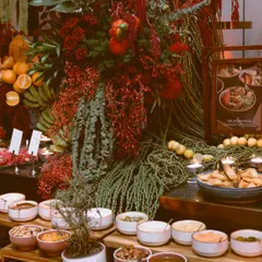 I love playing with bold colors, and this arrangement is a testament to that passion. Deep red florals cascade down, creating a powerful focal point amidst an array of curated bowls and platters, proving that a food station can be a true work of art.