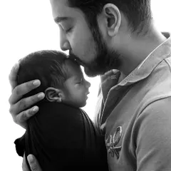 A father's gentle kiss on his newborn's forehead. This classic black and white shot is a simple yet profound expression of paternal love and protection.