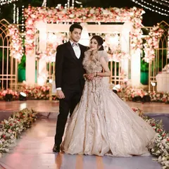 A picture perfect moment for the beautiful couple against the elegant reception stage we designed. The combination of soft florals, warm lighting, and intricate structures created a truly romantic backdrop.